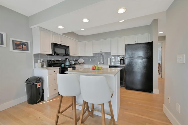 kitchen with baseboards, black appliances, light countertops, and decorative backsplash