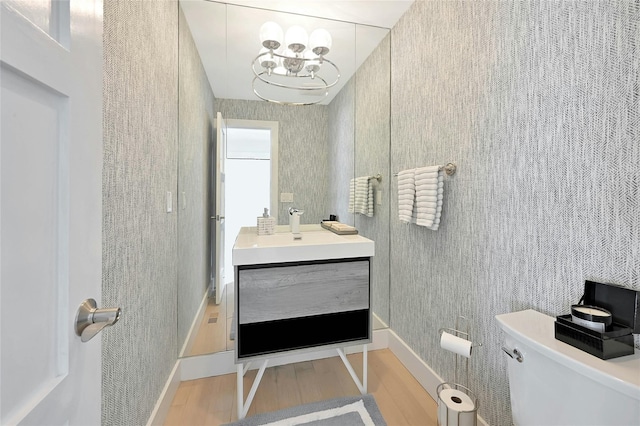bathroom featuring vanity, toilet, baseboards, and wood finished floors