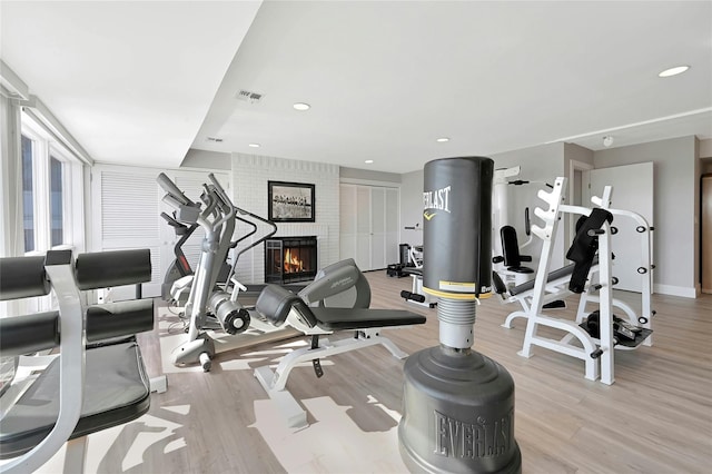 exercise room featuring recessed lighting, a fireplace, visible vents, and wood finished floors
