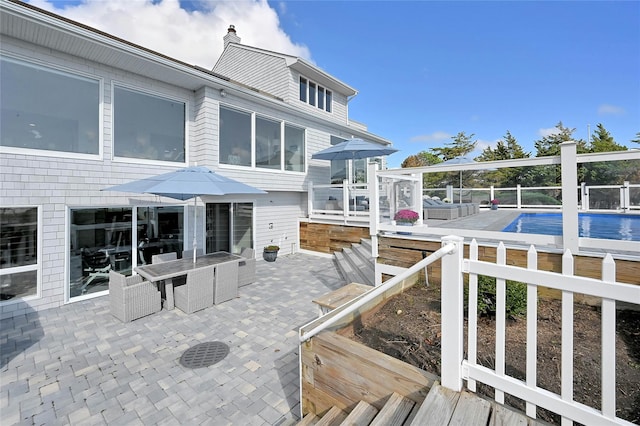 back of house with fence, a patio area, a fenced in pool, a chimney, and outdoor dining area