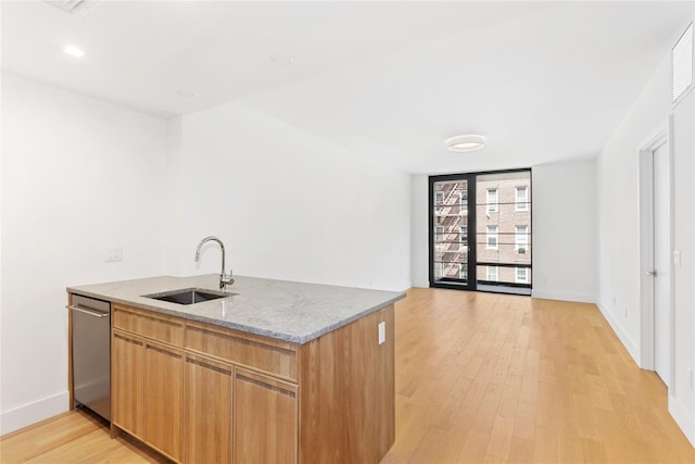 kitchen with dishwasher, light stone counters, a sink, a peninsula, and light wood-style floors