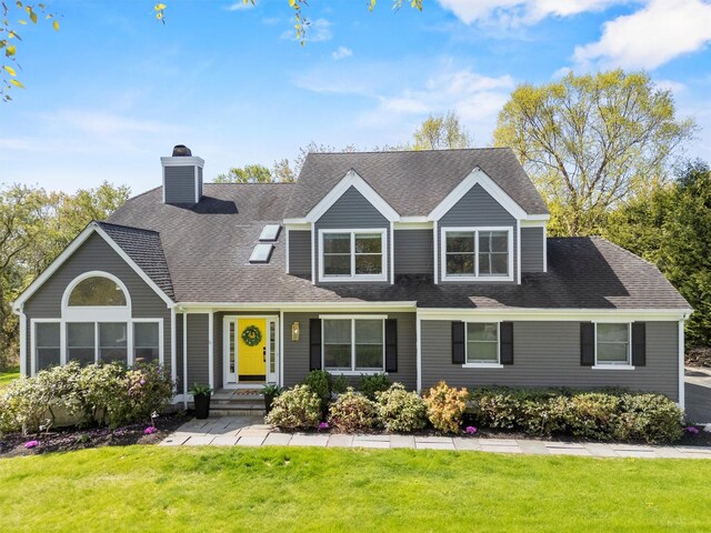 view of front of home with a chimney, a shingled roof, and a front lawn