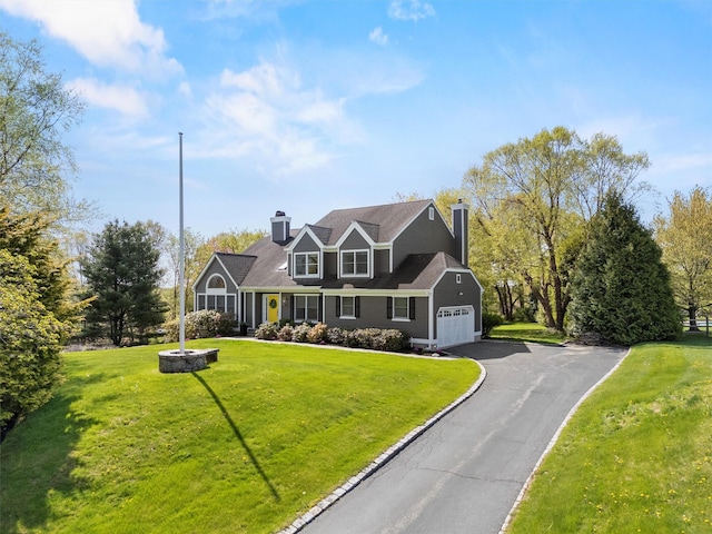 view of front of property featuring a front lawn, a chimney, a garage, and aphalt driveway