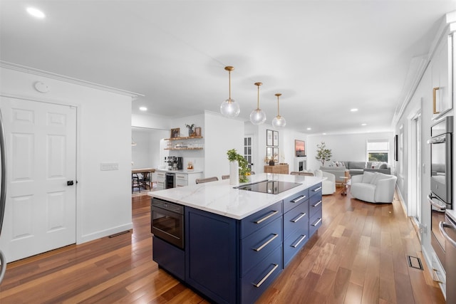 kitchen with black electric stovetop, wood finished floors, open floor plan, blue cabinets, and stainless steel oven