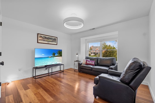living room with baseboards, visible vents, and wood finished floors