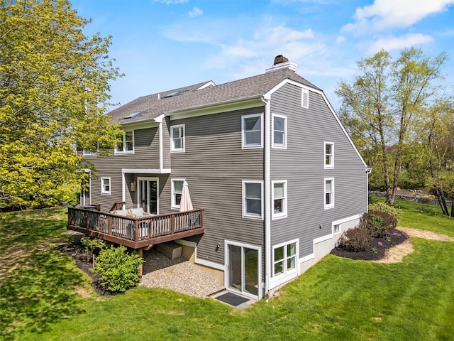 back of property with a chimney, a yard, a wooden deck, and roof with shingles