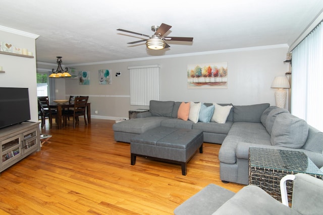 living room featuring crown molding, light wood-style flooring, a ceiling fan, and baseboards
