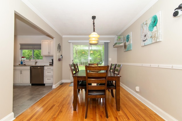 dining room with light wood-type flooring, ornamental molding, and baseboards