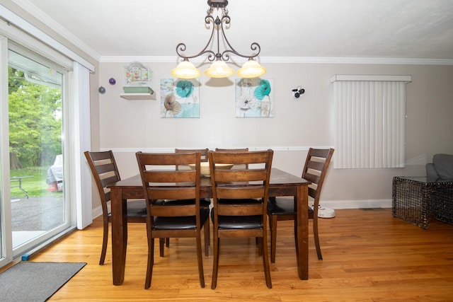 dining room with light wood finished floors, crown molding, baseboards, and a chandelier