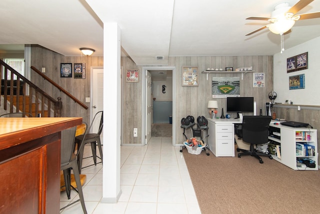 office area featuring ceiling fan, light tile patterned flooring, and wood walls