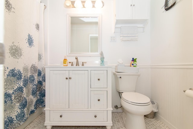 bathroom with toilet, wainscoting, vanity, and curtained shower