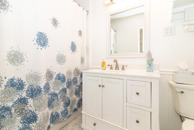 full bath featuring toilet, wainscoting, vanity, and a shower with shower curtain