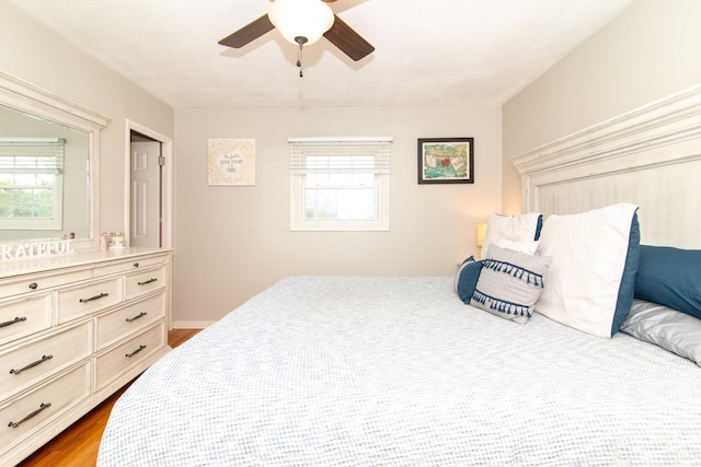 bedroom with multiple windows, ceiling fan, and wood finished floors