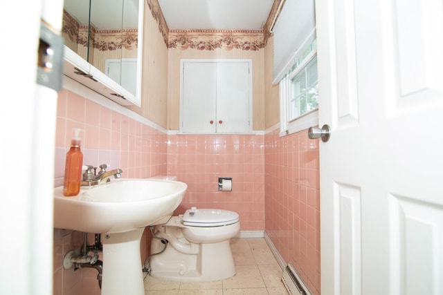 half bath featuring toilet, tile walls, a baseboard heating unit, and tile patterned floors