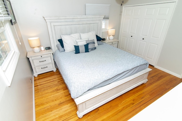 bedroom with light wood-type flooring, a closet, and baseboards