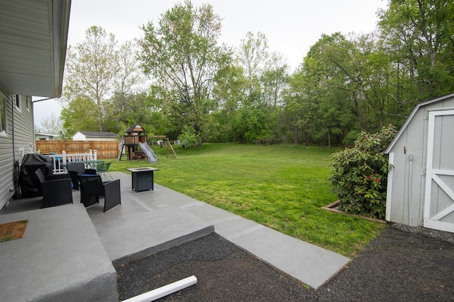 view of yard featuring a patio, a playground, a storage shed, an outdoor structure, and view of scattered trees