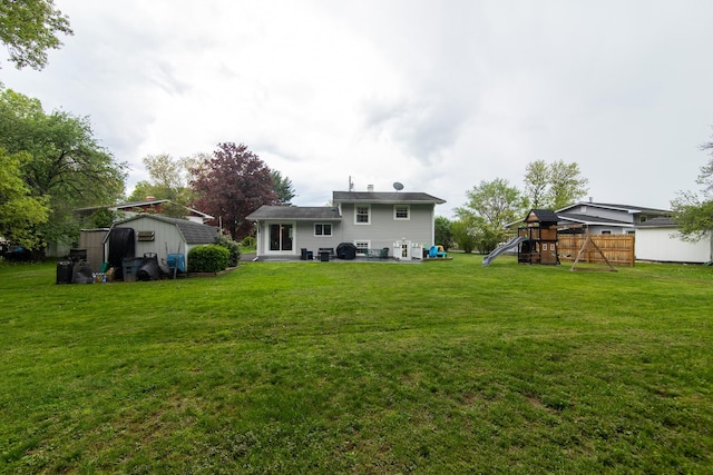 back of property featuring a storage unit, a playground, a patio, and an outbuilding