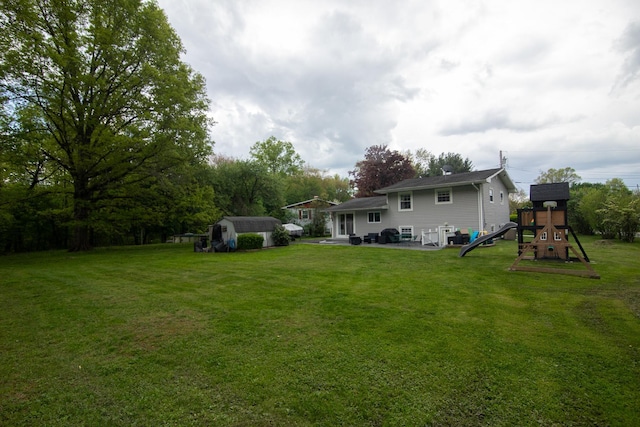 back of house with a playground, a shed, a patio area, a lawn, and an outbuilding