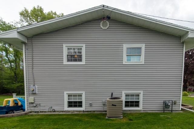 back of property with central AC and a lawn