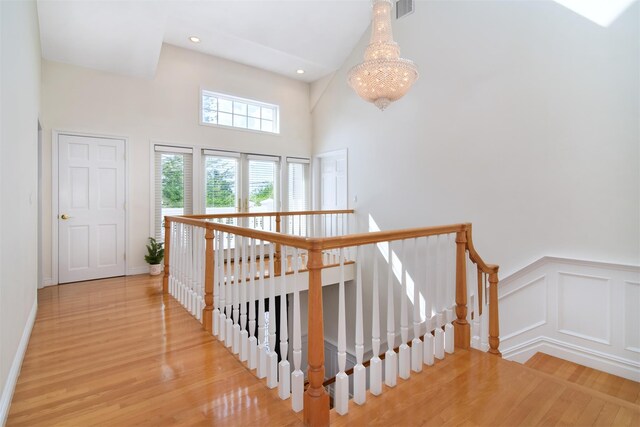 668 Francis St, Pelham, NY 10803 - stairway featuring recessed lighting, an inviting chandelier, a wainscoted wall, a towering ceiling, and wood finished floors