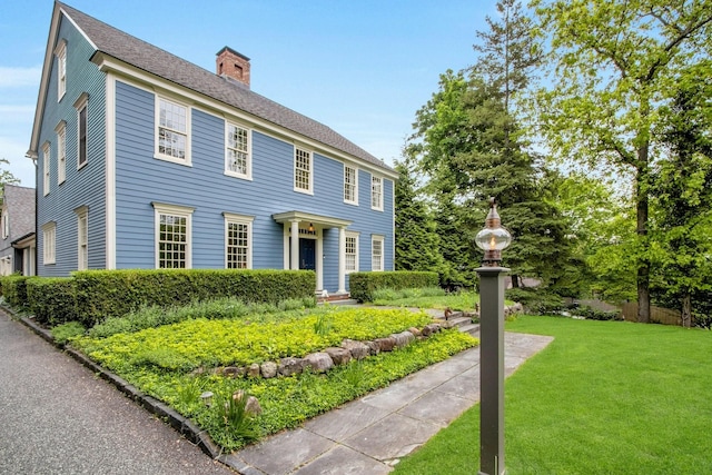colonial house with a chimney and a front yard