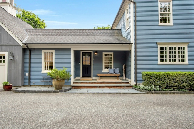 property entrance with covered porch and roof with shingles