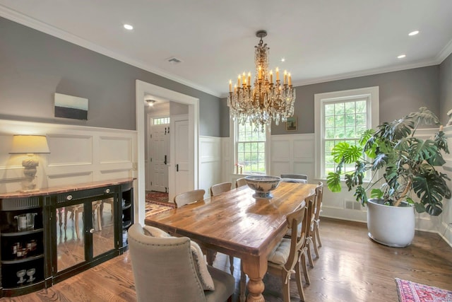 dining room with a decorative wall, a chandelier, wainscoting, wood finished floors, and ornamental molding