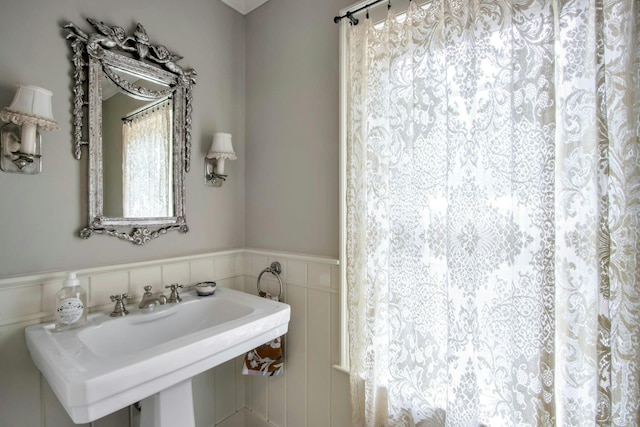 bathroom featuring a sink, wainscoting, and curtained shower