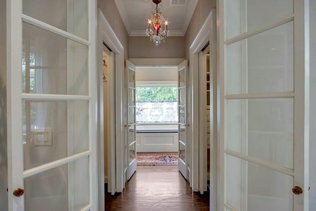 hallway with a chandelier, dark wood-type flooring, and crown molding