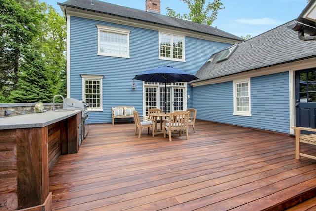 deck with outdoor dining space, exterior kitchen, and an outdoor bar