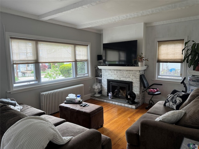 5 W Stone St, Newburgh, NY 12550 - living area with radiator heating unit, healthy amount of natural light, beamed ceiling, wood finished floors, and a fireplace