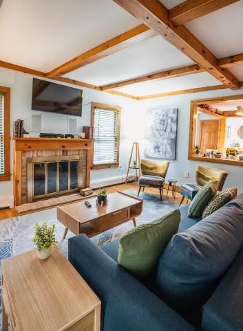 7181 County Highway 7, Roscoe, NY 12776 - living area featuring a glass covered fireplace, beamed ceiling, and wood finished floors