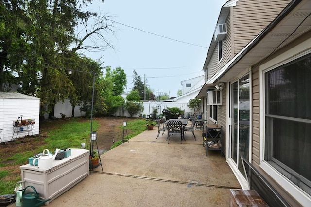 21 Potter Ln, Levittown, NY 11756 - view of patio featuring outdoor dining space, a storage unit, and an outbuilding