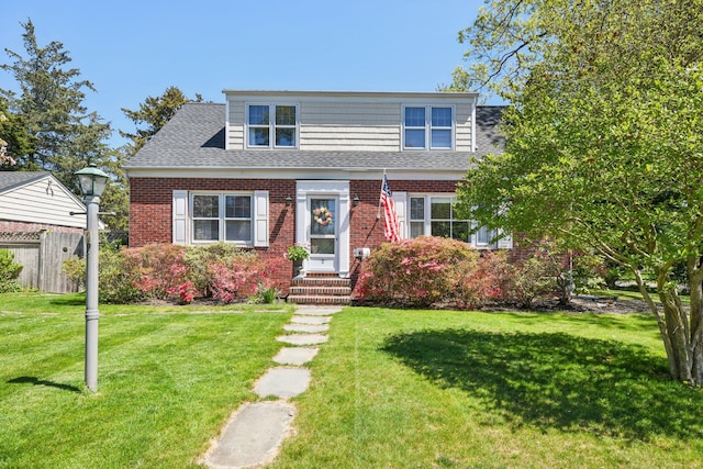 bungalow-style home featuring fence, a front lawn, a shingled roof, brick siding, and entry steps