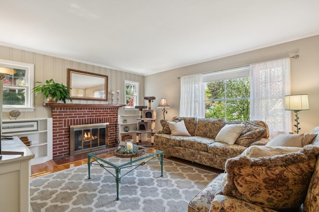 living room featuring crown molding, a brick fireplace, and wood finished floors