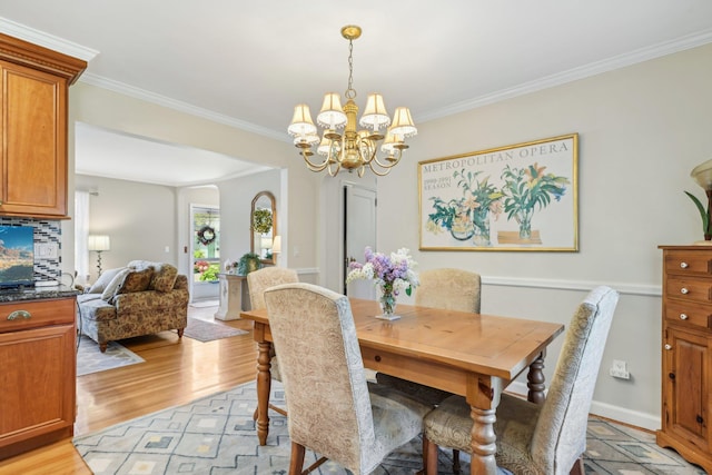 dining room with crown molding, a chandelier, and light wood-style flooring