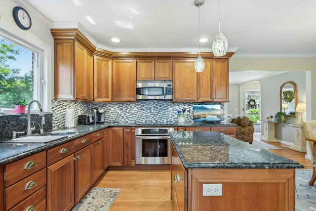 kitchen with brown cabinets, light wood-style floors, stainless steel appliances, and a sink
