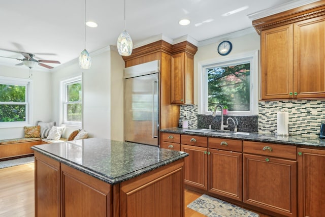 kitchen with light wood-type flooring, built in fridge, ornamental molding, and backsplash