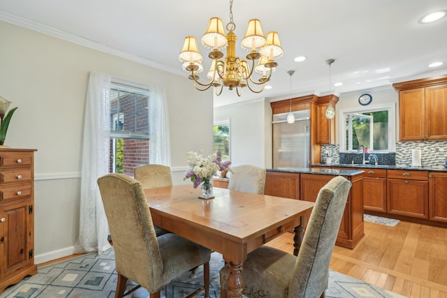 dining space featuring light wood finished floors, crown molding, a wealth of natural light, and an inviting chandelier