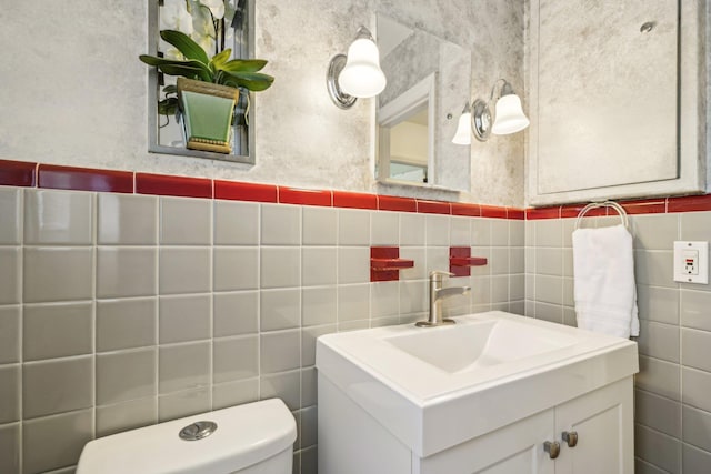 bathroom featuring toilet, tile walls, and vanity