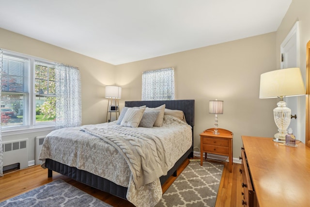 bedroom featuring wood finished floors, baseboards, and radiator heating unit