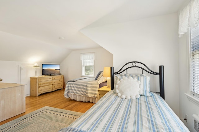bedroom with lofted ceiling, visible vents, and wood finished floors