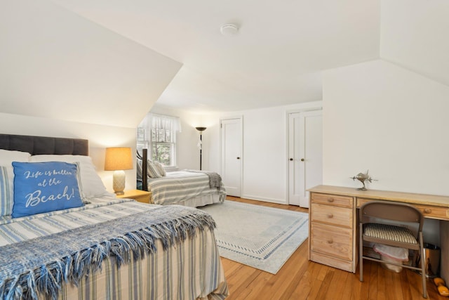bedroom with light wood-style flooring and vaulted ceiling