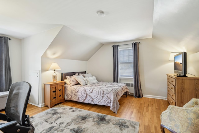 bedroom featuring radiator, light wood-style floors, vaulted ceiling, and baseboards