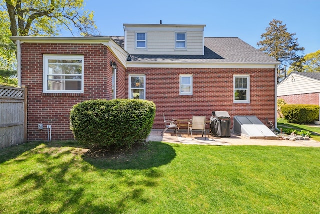 back of property featuring a lawn, a patio, and brick siding