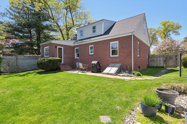 rear view of property with a gate, a patio area, brick siding, a yard, and a fenced backyard
