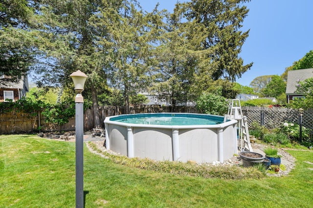 view of swimming pool with a yard, a fenced in pool, and a fenced backyard