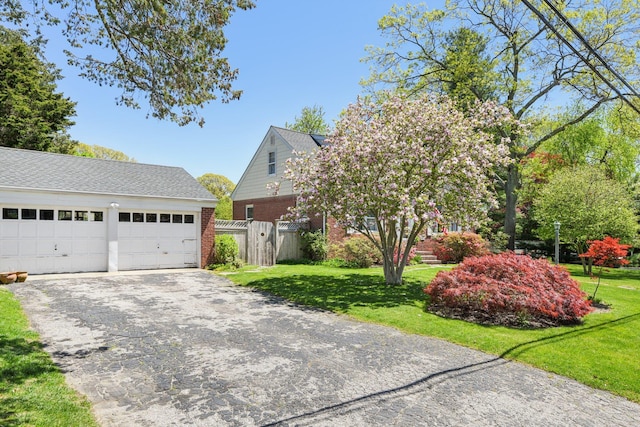 view of front facade featuring an outdoor structure, a garage, brick siding, and a front yard