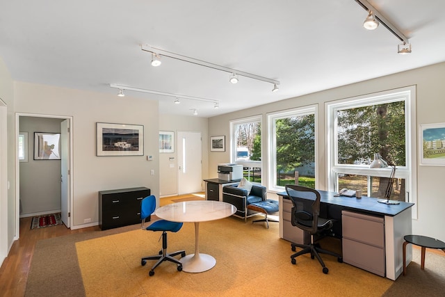 home office with rail lighting and light wood-style flooring