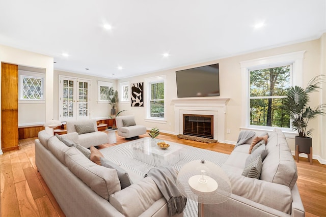 living room with recessed lighting, a glass covered fireplace, and light wood-style floors